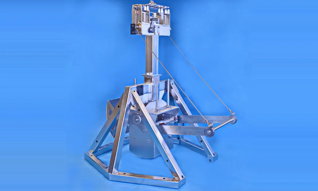 A stainless steel box corer on a blue studio background